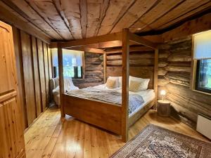 a bedroom with a bed in a log cabin at Villa Pukelo Arctic Lodge with wifi sauna 4 poster bed fireplace in Salla