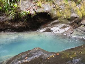 a pool of blue water next to a rock formation at Studio près de la mer et marina in Gourbeyre