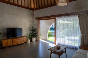 a living room with a tv and a large window at Casa Nova Villa Uluwatu in Uluwatu