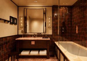 a bathroom with a tub and a sink and a mirror at Bourbon Hôtel in Courchevel