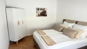 a white bedroom with a bed and a cabinet at Apartment Niki in Siegendorf im Burgenland