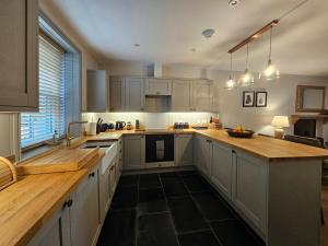 a kitchen with white cabinets and a wooden counter top at Balnain Street Cottage in Inverness
