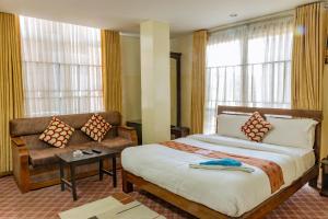 a bedroom with a bed and a couch and windows at Hotel Swastik in Kathmandu