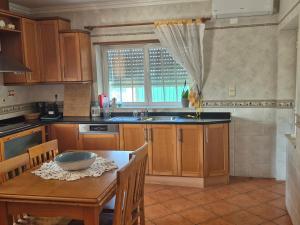 a kitchen with wooden cabinets and a table with a bowl on it at Toca dos Coelhos in Silveira +2 photos