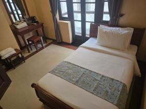 a bedroom with a bed and a desk and window at LT Home Stay in Siem Reap