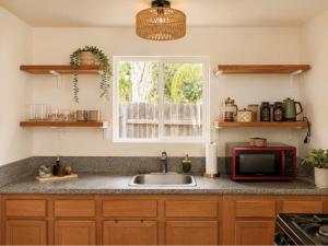 a kitchen counter with a microwave and a sink at Ojai Pixie House in Ojai