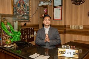 a man sitting at a desk in a room with his hands clasped at Hotel Swastik in Kathmandu