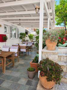 a patio with tables and chairs and potted plants at Athina Guesthouse in Hydra