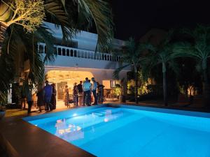 a group of people standing around a swimming pool at night at Nomads Kodjoviakopé in Lomé