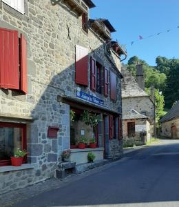 a stone building with red shutters on a street at Auberge des Volcans in Saint-Chamant