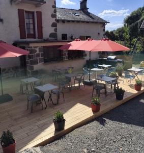 a wooden deck with tables and chairs and umbrellas at Auberge des Volcans in Saint-Chamant +9 photos