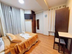 a bedroom with a bed and a table and a desk at Hotel Dubái in Tacna