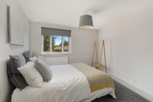 a white bedroom with a bed and a window at Malvern House in Banbury
