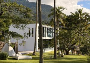a building with palm trees in front of it at DPNY Beach Hotel & SPA Ilhabela in Ilhabela