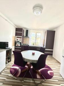 a kitchen with a white table and purple chairs at Apartament Uricani in Uricani