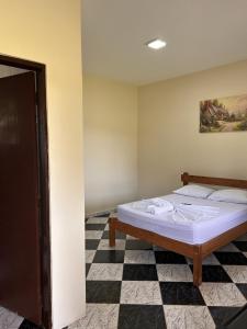 a bedroom with a bed with a checkered floor at Hotel Harmonia Sarapuí in Sarapuí