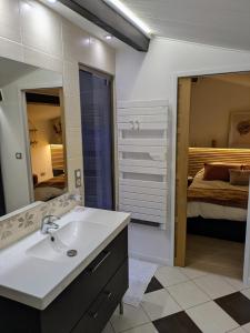 a bathroom with a sink and a bedroom with a bed at Charmant Cocon, terrasse proche Clermont in Tallende