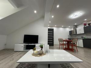 a living room with a white table and a kitchen at Apartmány Tonny in Jáchymov