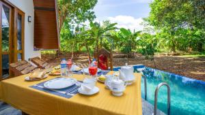 a yellow table with food and drinks on it next to a pool at Sunrise Villa Pidurangala in Sigiriya