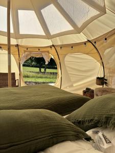 a bed in a tent with a view of a field at Glamping, Tåsinge - Svendborg in Svendborg +5 photos