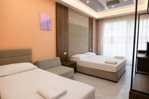 a hotel room with two beds and a chair at AMMEN Rooms in Shëngjin