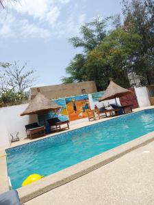 a pool with chairs and umbrellas next to a building at les baobabs in Mbour