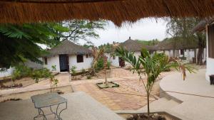 a courtyard with huts and a table and trees at les baobabs in Mbour