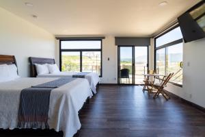 a hotel room with two beds and a balcony at Flor de Garambullo, Valle de Guadalupe in Valle de Guadalupe