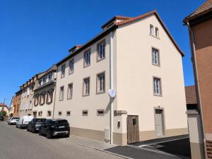 a large white building with cars parked in front of it at Le Clos d'Ingersheim in Ingersheim