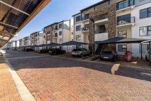 a brick street with cars parked in front of a building at #AlimamaSpaces The Contemporary Retreat in Midrand