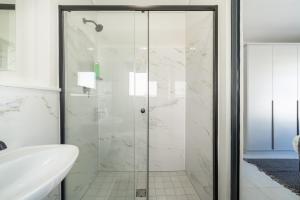 a glass shower in a bathroom with a sink at #AlimamaSpaces The Contemporary Retreat in Midrand +18 photos
