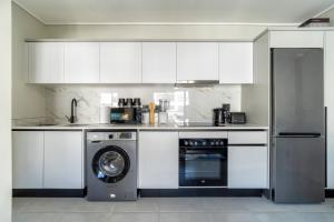 a kitchen with white cabinets and a washing machine at #AlimamaSpaces The Contemporary Retreat in Midrand