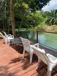 a wooden deck with white chairs and a table and water at Khaosok River Camp in Khao Sok National Park