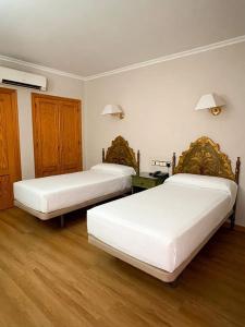 two beds in a room with wooden floors at Hotel Salvador in Bailén