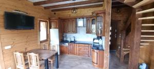 a kitchen with wooden cabinets and a table and a tv at Bacówka pod Ślężą in Sulistrowice +16 photos