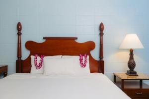 a bed with white pillows and a wooden headboard at Waikiki Heritage Hotel in Honolulu