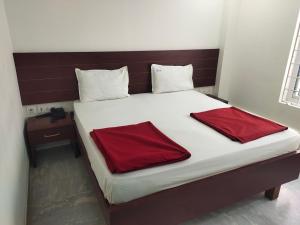 a large bed with two red pillows on it at Raya Raj Anugraha in Kumbakonam