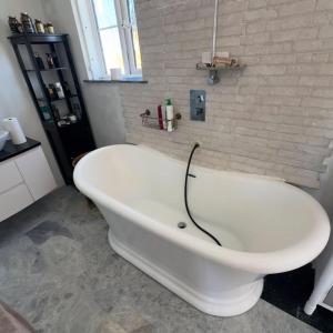 a white bath tub in a bathroom with a brick wall at Room in Estepona
