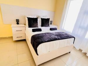 a bedroom with a large white bed with black pillows at MrP Guest House in Kokstad
