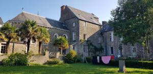 a large stone building with palm trees in front of it at La Miséricorde-Deluxe room with kids room in Coutances