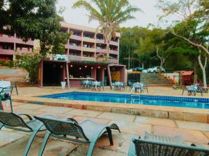 a resort with a pool and chairs and a building at Hotel Sinhá in Tianguá
