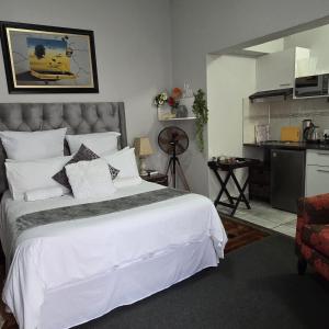 a bedroom with a large white bed and a kitchen at The Wentworth Guest House in Krugersdorp