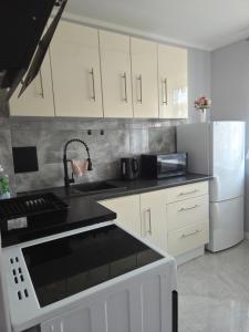 a kitchen with white cabinets and a black counter top at Apartament cisza i spokój in Toruń