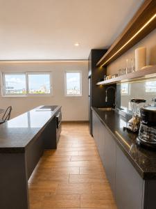 a large kitchen with black counter tops and wooden floors at Modernos departamentos tipo LOFT a dos calles del estadio in Boca del Río +65 photos