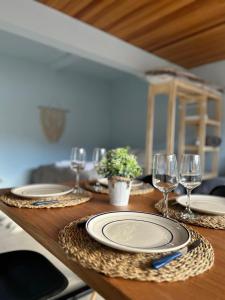 a wooden table with plates and wine glasses on it at Dpto General Roca 1355 - La Loggia in San Martín de los Andes