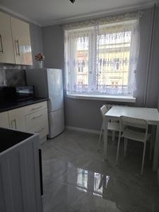 a kitchen with a table and a refrigerator and a window at Apartament cisza i spokój in Toruń