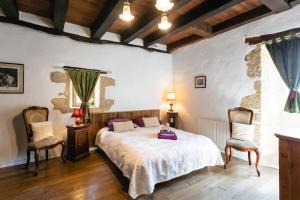 a bedroom with a bed and two chairs at La Tour Aliénor, maison de caractère du XIVème siècle in Beynac-et-Cazenac