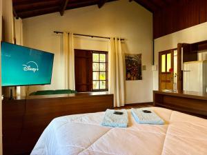 a bedroom with a bed and a flat screen tv at Atelier-Aconchego e Fitness in Pirenópolis