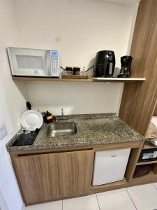 a kitchen with a sink and a microwave at Flat em hotel Promenade Itaguaí in Itaguaí