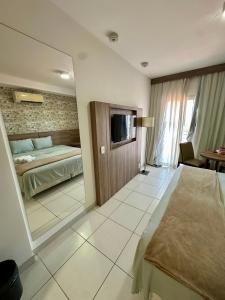 a bedroom with a bed and a television in it at Flat em hotel Promenade Itaguaí in Itaguaí